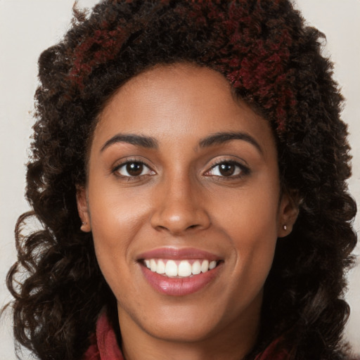 Joyful black young-adult female with long  brown hair and brown eyes