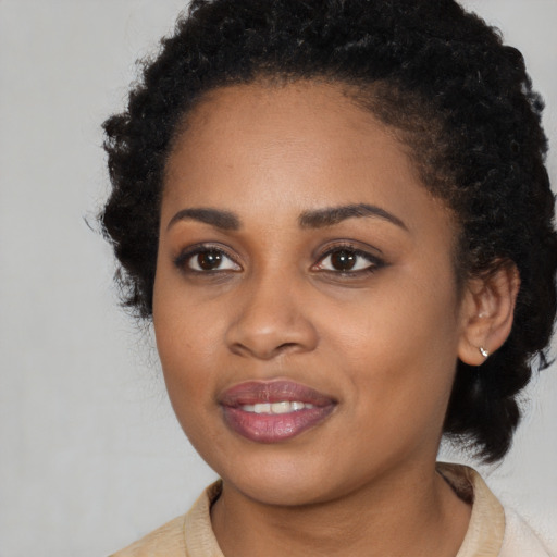 Joyful black young-adult female with long  black hair and brown eyes
