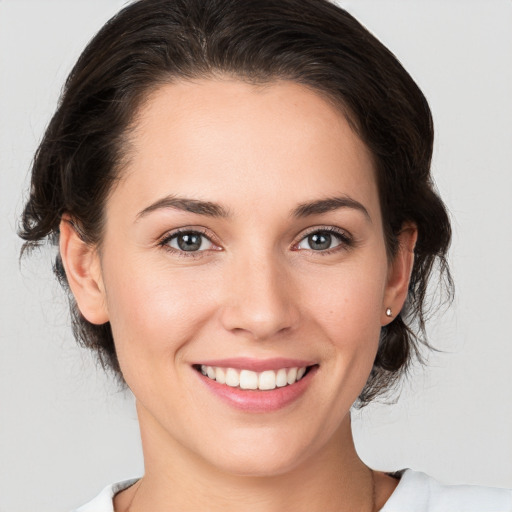 Joyful white young-adult female with medium  brown hair and grey eyes