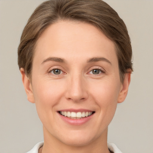 Joyful white young-adult female with short  brown hair and green eyes