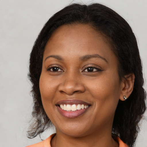 Joyful black young-adult female with long  brown hair and brown eyes