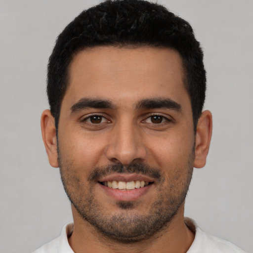 Joyful latino young-adult male with short  black hair and brown eyes