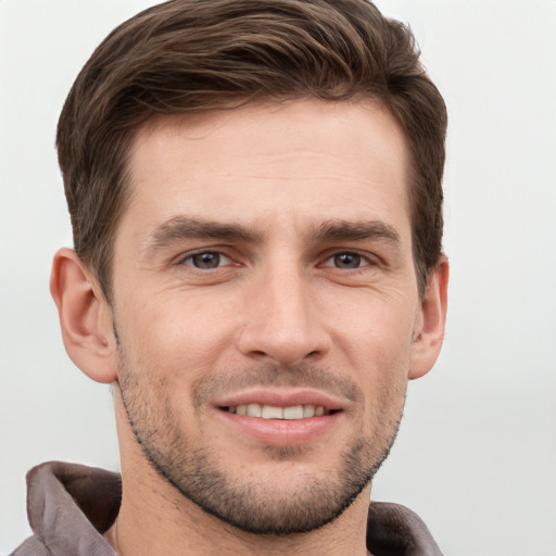 Joyful white young-adult male with short  brown hair and grey eyes