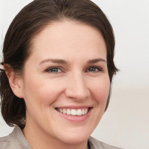 Joyful white young-adult female with medium  brown hair and grey eyes