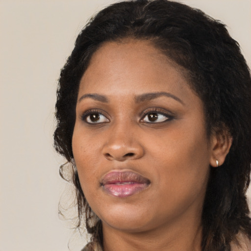 Joyful black young-adult female with long  black hair and brown eyes