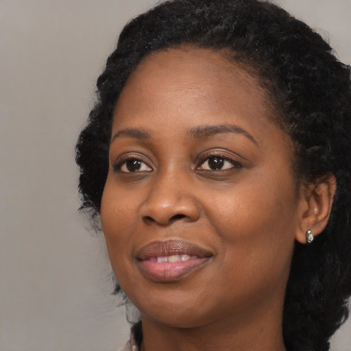 Joyful black young-adult female with long  black hair and brown eyes