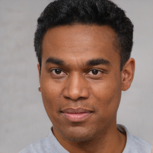 Joyful black young-adult male with short  black hair and brown eyes