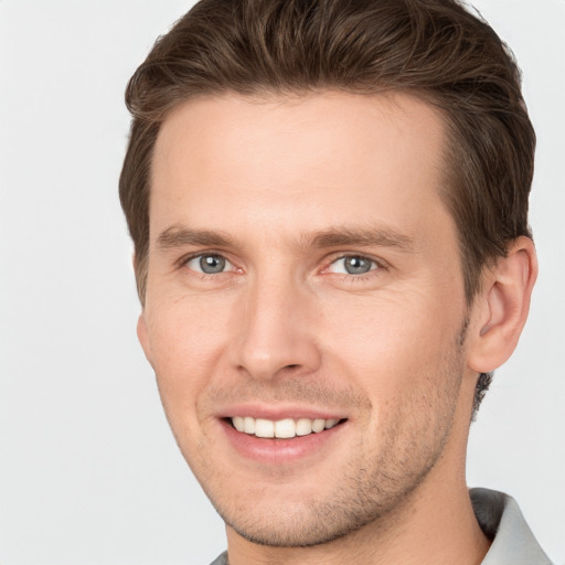 Joyful white young-adult male with short  brown hair and grey eyes