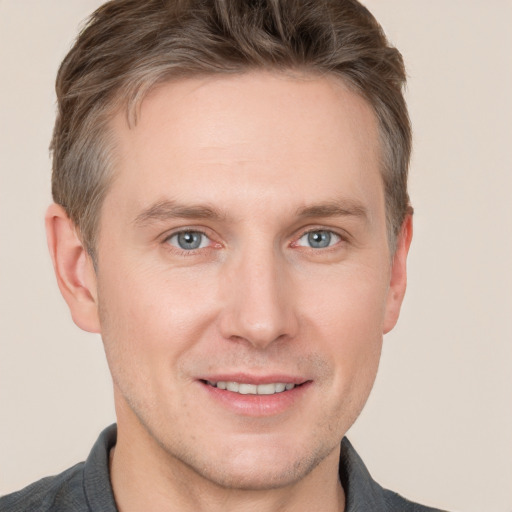 Joyful white young-adult male with short  brown hair and grey eyes