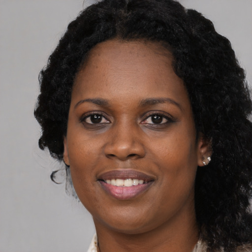 Joyful black young-adult female with long  black hair and brown eyes