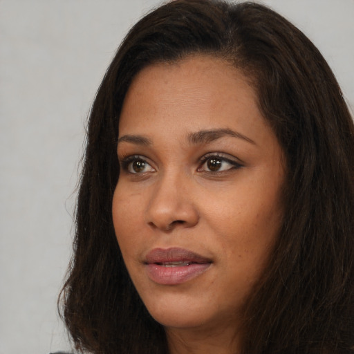 Joyful black young-adult female with long  brown hair and brown eyes