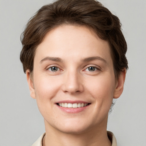 Joyful white young-adult female with short  brown hair and grey eyes