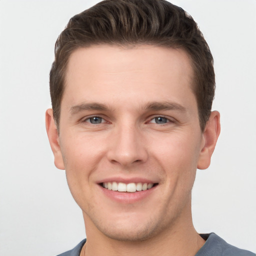 Joyful white young-adult male with short  brown hair and grey eyes