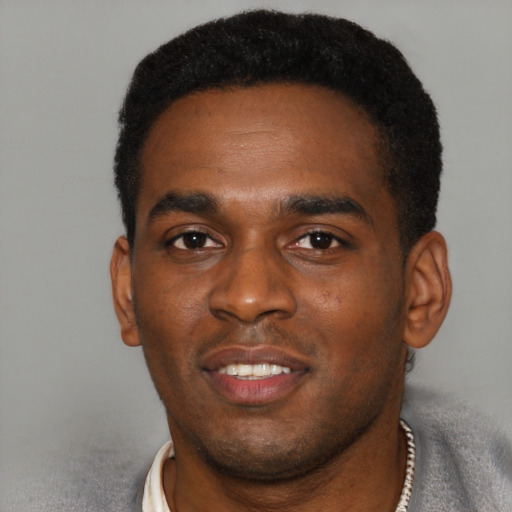 Joyful black young-adult male with short  black hair and brown eyes