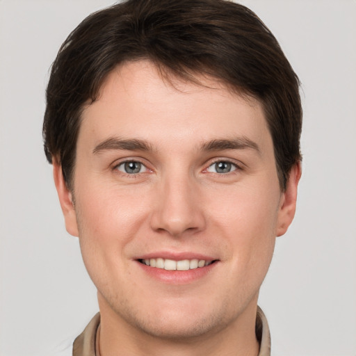 Joyful white young-adult male with short  brown hair and grey eyes