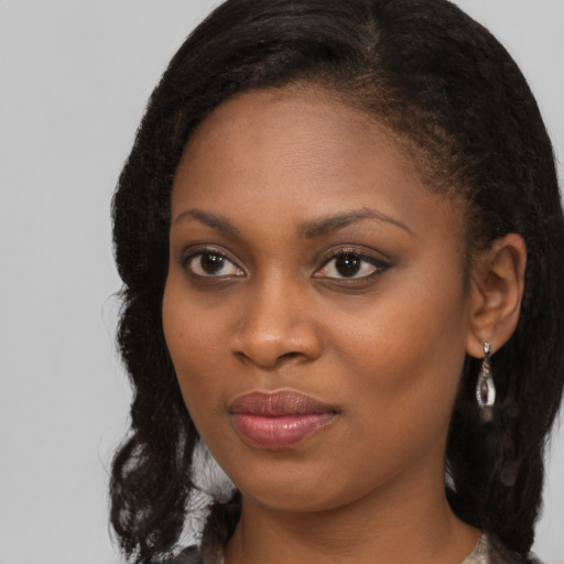 Joyful black young-adult female with long  black hair and brown eyes