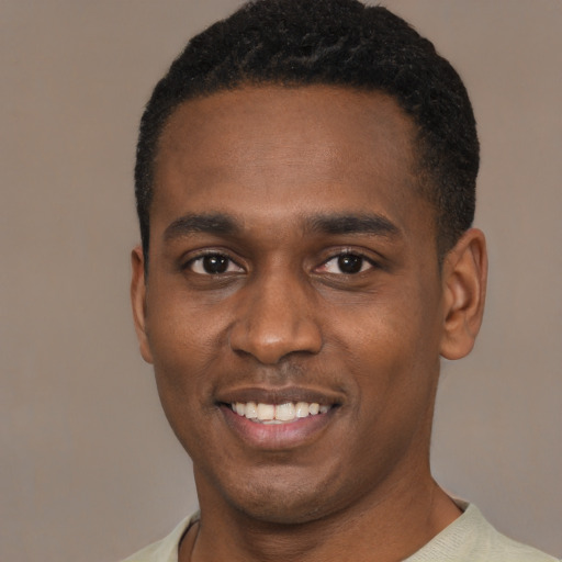 Joyful black young-adult male with short  black hair and brown eyes