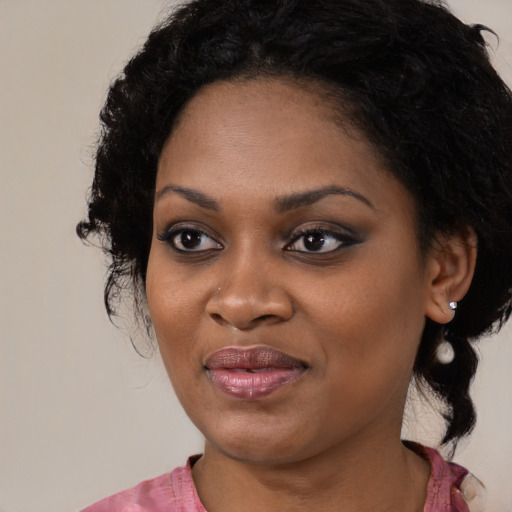 Joyful black young-adult female with long  black hair and brown eyes