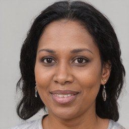 Joyful black young-adult female with long  brown hair and brown eyes