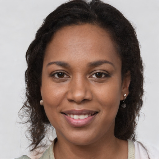 Joyful black young-adult female with long  brown hair and brown eyes
