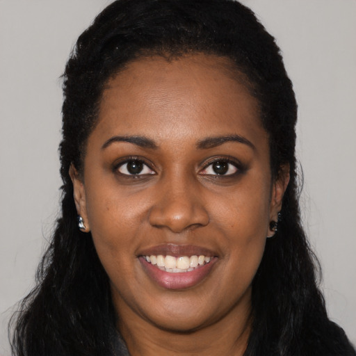 Joyful black young-adult female with long  black hair and brown eyes