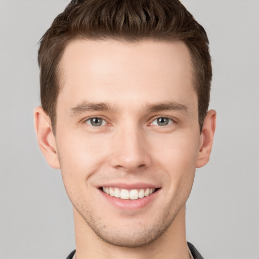 Joyful white young-adult male with short  brown hair and grey eyes