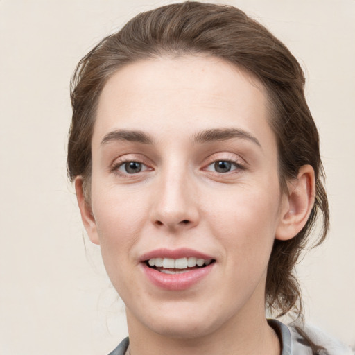 Joyful white young-adult female with medium  brown hair and grey eyes