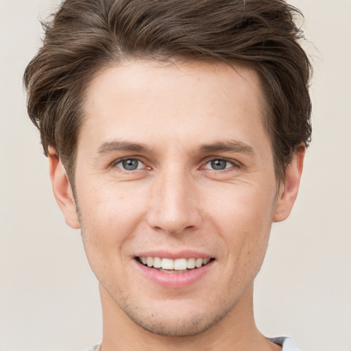 Joyful white young-adult male with short  brown hair and grey eyes