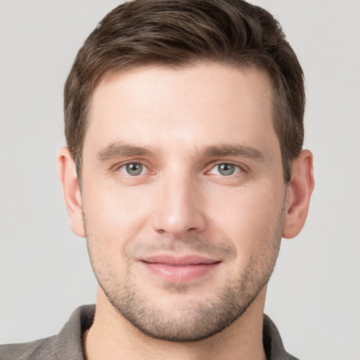 Joyful white young-adult male with short  brown hair and grey eyes