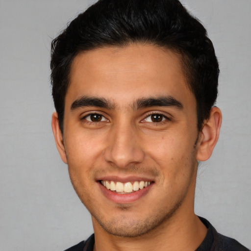 Joyful latino young-adult male with short  brown hair and brown eyes