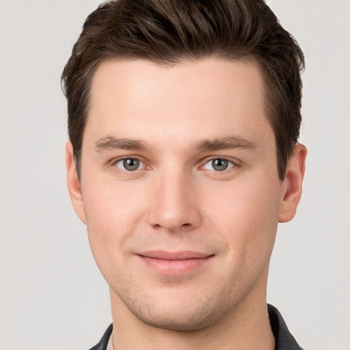 Joyful white young-adult male with short  brown hair and grey eyes