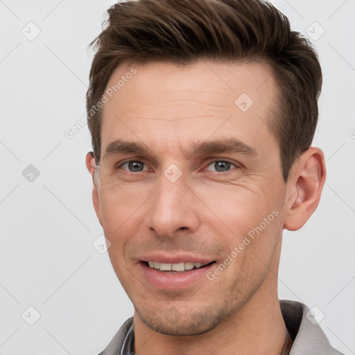 Joyful white young-adult male with short  brown hair and grey eyes