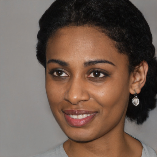 Joyful black young-adult female with short  black hair and brown eyes