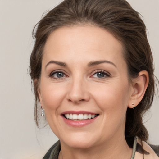 Joyful white young-adult female with medium  brown hair and grey eyes