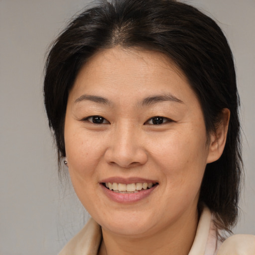 Joyful asian adult female with medium  brown hair and brown eyes