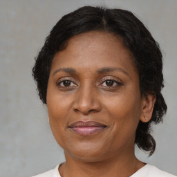 Joyful black adult female with medium  brown hair and brown eyes