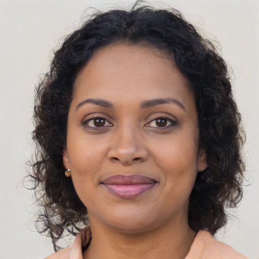 Joyful black young-adult female with long  brown hair and brown eyes