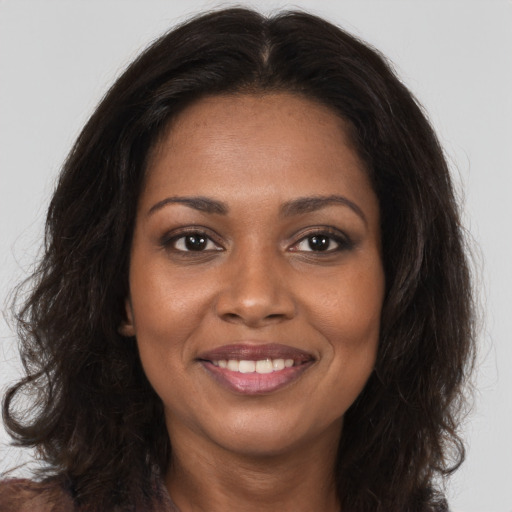 Joyful black young-adult female with long  brown hair and brown eyes