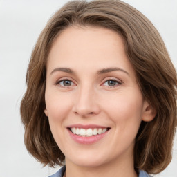 Joyful white young-adult female with medium  brown hair and green eyes