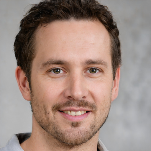 Joyful white young-adult male with short  brown hair and grey eyes