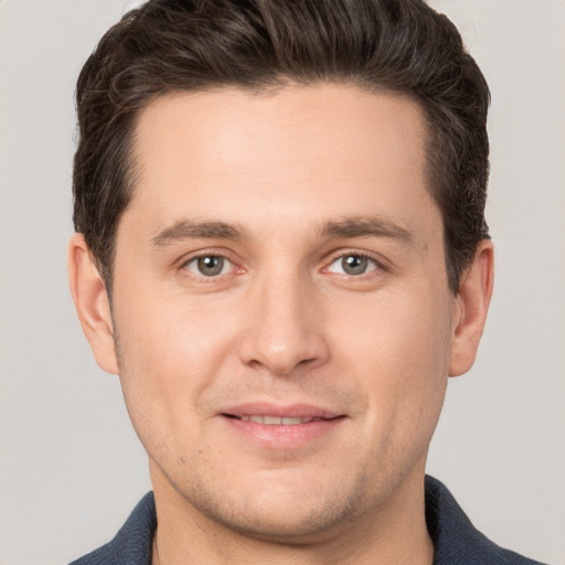 Joyful white young-adult male with short  brown hair and grey eyes