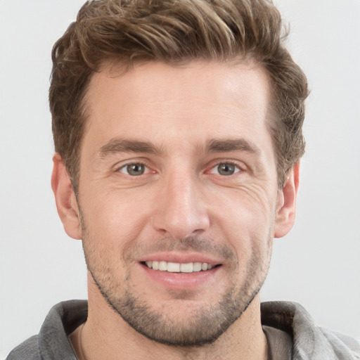 Joyful white young-adult male with short  brown hair and grey eyes