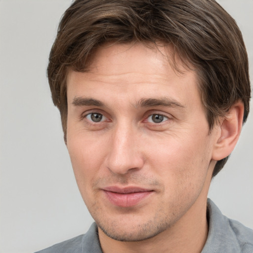 Joyful white young-adult male with short  brown hair and grey eyes