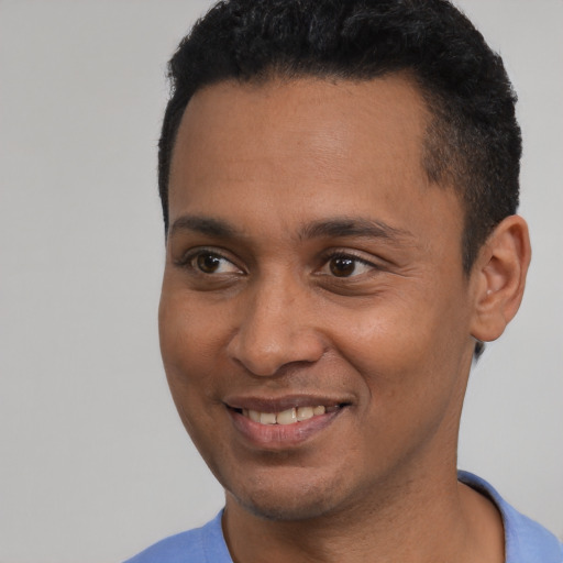 Joyful black young-adult male with short  black hair and brown eyes