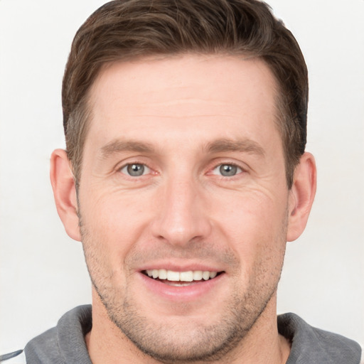 Joyful white young-adult male with short  brown hair and grey eyes