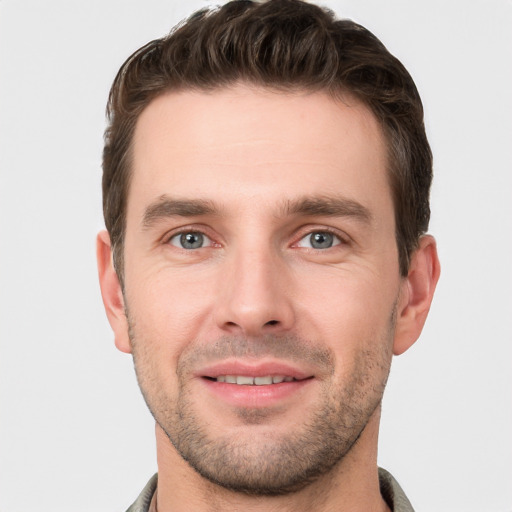 Joyful white young-adult male with short  brown hair and grey eyes