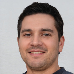 Joyful white young-adult male with short  black hair and brown eyes