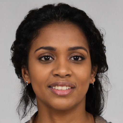 Joyful black young-adult female with long  black hair and brown eyes