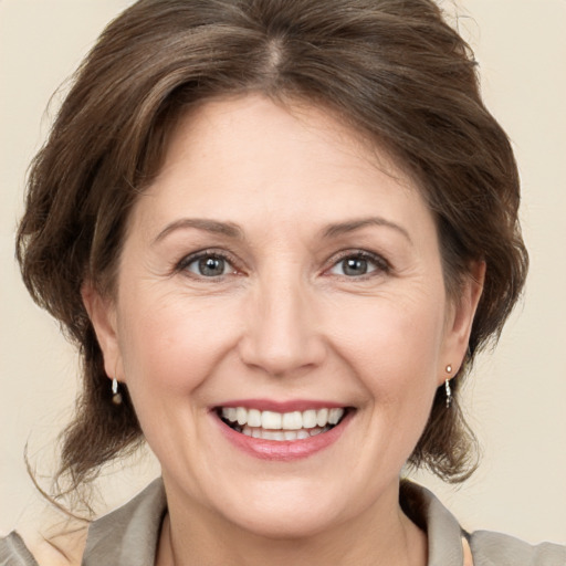 Joyful white adult female with medium  brown hair and grey eyes