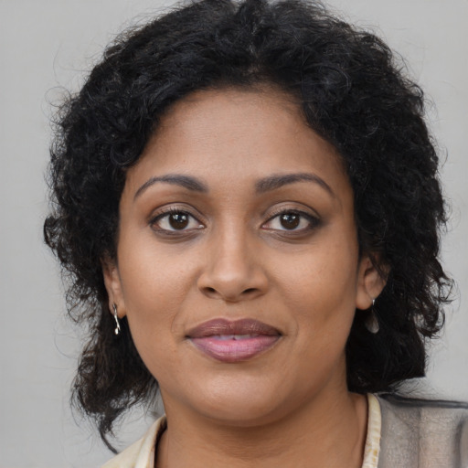 Joyful black young-adult female with long  brown hair and brown eyes